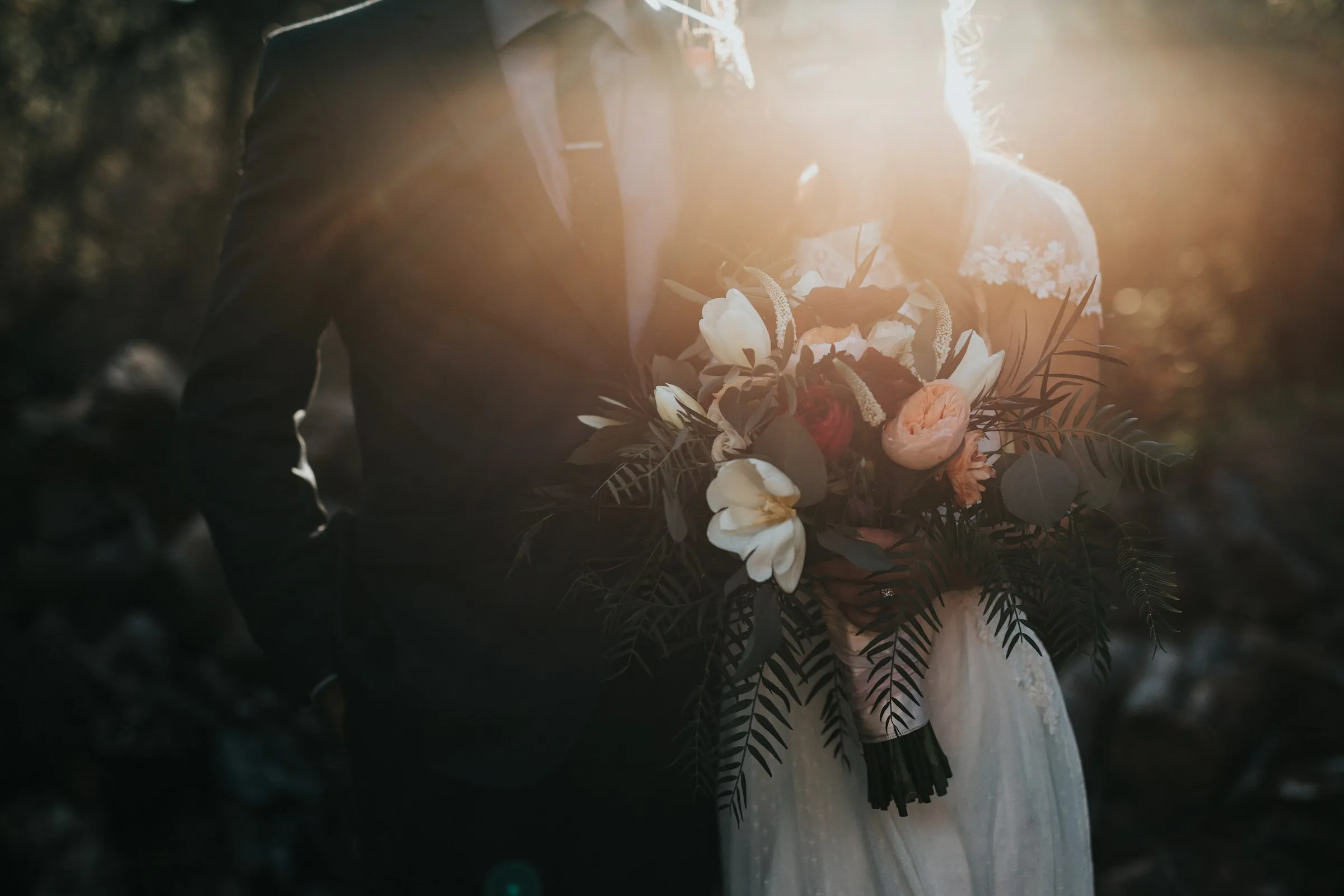 Bride and groom kissing beneath a wind-lifted veil